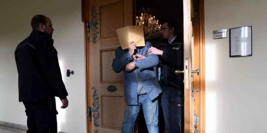 An Händen und Füssen gefesselt wird der angeklagte Vater in einer Verhandlungspause aus dem Sitzungssaal in Ellwangen geführt. Foto: Stefan Puchner/dpa