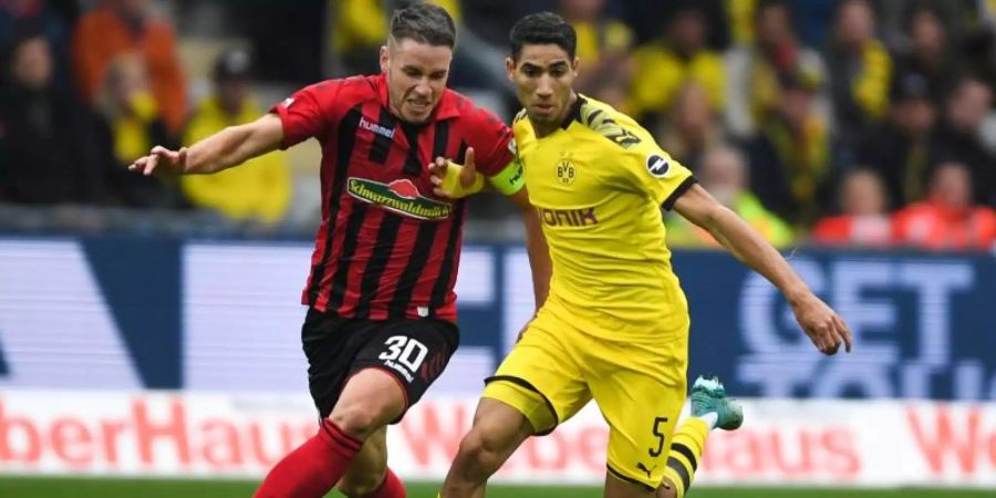 Freiburgs Christian Günter (l) und Dortmunds Achraf Hakimi (r) im Laufduell um den Ball. Foto: Patrick Seeger/dpa