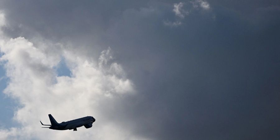 Ein Flugzeug fliegt nach seinem Sart am Flughafen München auf dunkle Wolke zu.