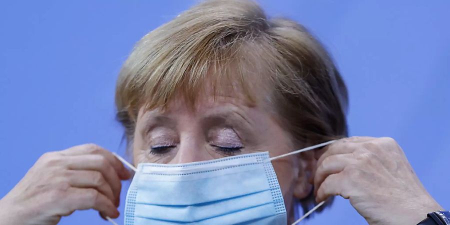 Bundeskanzlerin Angela Merkel (CDU) setzt ihre Gesichtsmaske nach ihrer Pressekonferenz auf. Foto: Odd Andersen/AFP/POOL/dpa