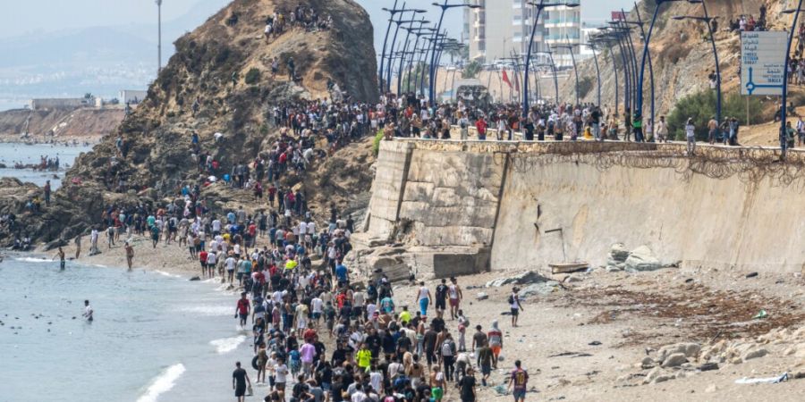 Menschen laufen am Strand entlang, nachdem sie versucht hatten, von der marokkanischen Stadt Fnideq im Norden in die spanische Exklave Ceuta zu gelangen. Foto: STR/AP/dpa