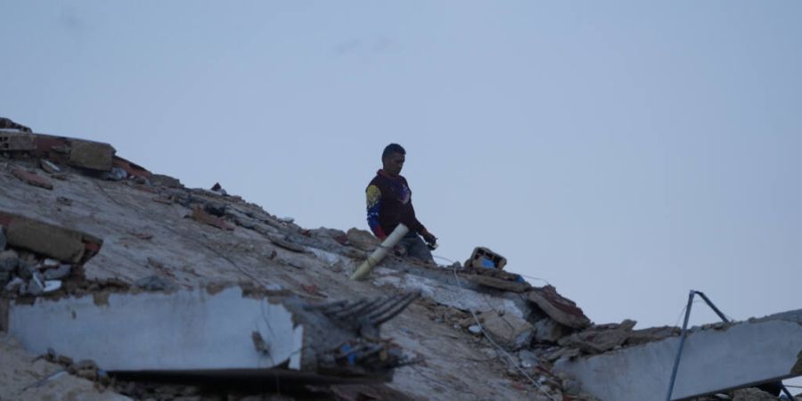 dpatopbilder - Ein Mann geht zwischen den Trümmern eines Gebäudes, das bei den Erdbeben in La Guaira eingestürzt ist. Foto: Fernando Vergara/AP/dpa