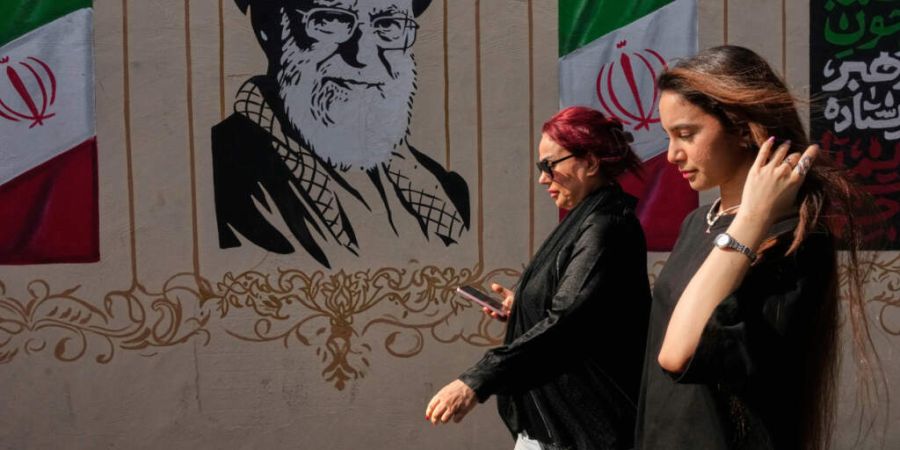 ARCHIV - Frauen gehen in der Innenstadt an einem Porträt des verstorbenen iranischen Obersten Führers Ayatollah Ali Chamenei, der bei einem Angriff der USA und Israels am 28. Februar ...