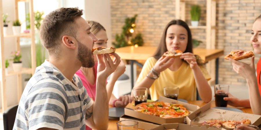 Freunde sitzen am Tisch und essen.