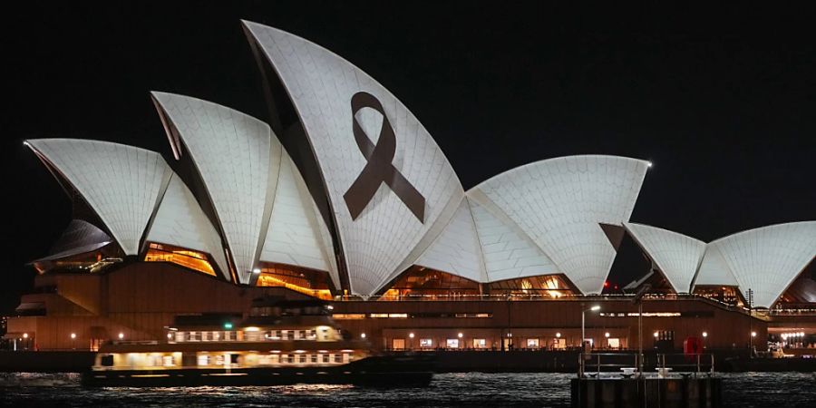 Das Opernhaus von Sydney wird im Rahmen eines nationalen Tages der Trauer nach dem tödlichen Messerangriff in einem Einkaufszentrum mit einer schwarzen Schleife angeleuchtet. In der australischen Metropole ist die Polizei am Montag erneut wegen eines Stich-Angriffs ausgerückt. Foto: Mark Baker/AP