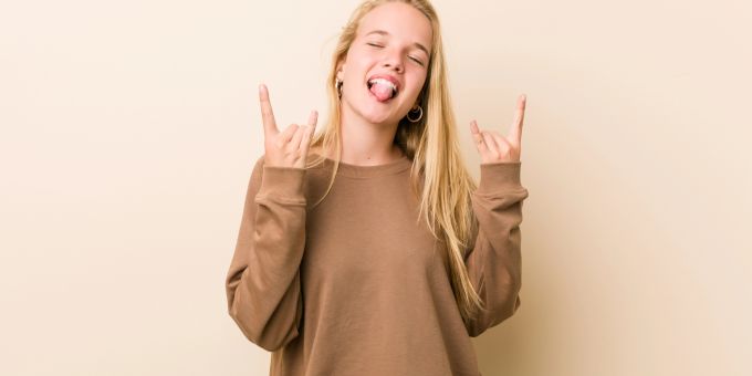 Jugendliche switchen oft zwischen verschiedenen Identitäten. Junges Mädchen zeigt Rock-Geste