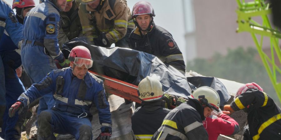 Rettungskräfte tragen die Leiche eines Anwohners, der beim Einschlag einer russischen Rakete in ein Wohnhaus während eines massiven Luftangriffs getötet wurde. Foto: Efrem Lukatsky/A...