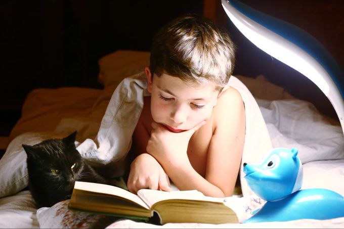 Manche Kinder lesen gerne noch etwas vor dem Schlafengehen. Junge liest vorm Schlafengehen.
