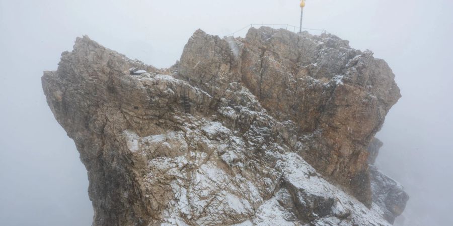 Nebelwolken umhüllen bei Schneetreiben auf der Zugspitze die Aussichtsplattform mit dem Gipfelkreuz (Archivbild). Aus 
mehreren Bergsteigergruppen wurden Notrufe abgesetzt, nachdem sie aufgrund von Witterung und Neuschnee auf etwa 2500 Metern Höhe nicht mehr weiterkamen.