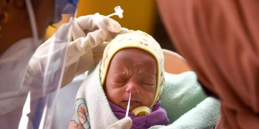 Eine Medizinerin entnimmt einem Baby in einem Krankenhaus einen Nasenabstrich für einen Corona-Test. Foto: Farooq Sayed/PTI/dpa