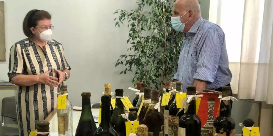 Kulturministerin Lina Mendoni spricht mit einem Restaurator vor einigen der wertvollen Fundflaschen aus dem Ex-Königspalast. Foto: -/Griechisches Kulturministerium/dpa