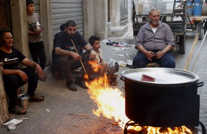 Menschen bereiten Essen in einem grossen Topf über offenem Feuer vor. (Symbolbild) Suppe