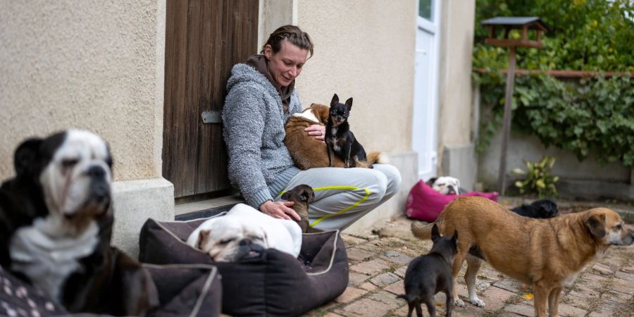 Stephanie Badura sitzt vor ihrem Haus und streichelt ihre Pflegehunde.