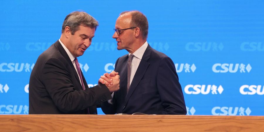 CSU-Chef Markus Söder steht mit Friedrich Merz,Vorsitzender der CDU, nach dessen Rede auf der Bühne.