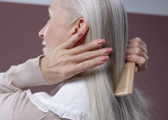 Graues Haar kämmt sich leichter, wenn man Feuchtigkeitsshampoos und pflegende Conditioner verwendet. Frau kämmen Feuchtigkeitsshampoo Conditioner