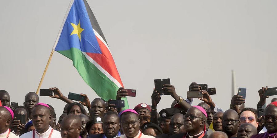 Menschen warten mit ihren Handys in der Hand auf die Ankunft von Papst Franziskus am Flughafen von Juba. Foto: Gregorio Borgia/AP/dpa