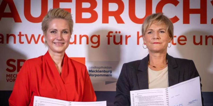 Manuela Schwesig (SPD, l), die Ministerpräsidentin von Mecklenburg-Vorpommern, und Simone Oldenburg (r), die Fraktionschefin der Linken im Landtag von Mecklenburg-Vorpommern, zeigen den unterzeichneten Koalitionsvertrag zwischen SPD und der Linken für eine gemeinsame Regierungsbildung in Mecklenburg-Vorpommern. Foto: Jens Büttner/dpa-Zentralbild/dpa