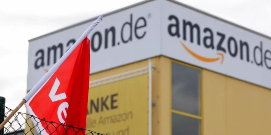 Eine Verdi-Fahne hängt während eines Streiks am Zaun eines Amazon-Versandzentrums (Archivbild). Foto: Jan Woitas/dpa-Zentralbild/dpa