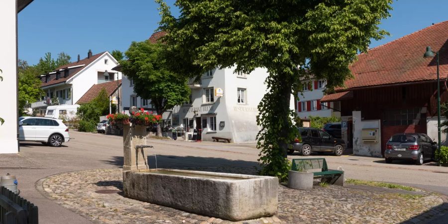 Der Dorfbrunnen in Känerkinden mit einer Ruhebank.