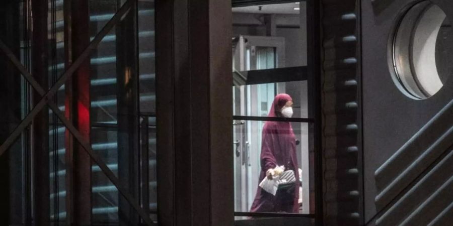Eine verschleierte Frau mit Mund-Nasen-Bedeckung verlässt eine Chartermaschine und betritt einen abgeschirmten Bereich der Bundespolizei am Flughafen Frankfurt. Foto: Boris Roessler/dpa