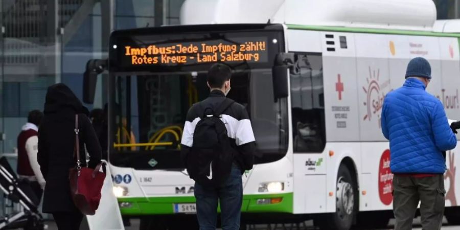 Menschen stehen in Salzburg in einer Warteschlange vor einem Impfbus. Foto: Barbara Gindl/APA/dpa