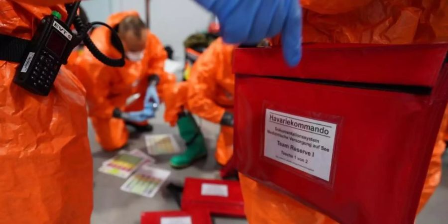 Einsatzkräfte des Havariekommandos bereiten sich während einer Grossübung zur Vorbereitung auf Notfälle im Seuchenschutz im Hamburger Hafen auf ihren Einsatz vor. Foto: Marcus Brandt/dpa
