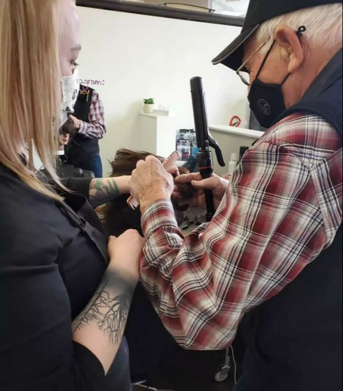 Der 79-Jährige übt an den Haaren einer Puppe, wie man mit dem Lockenstab umgeht. Good News Rentner Kosmetik