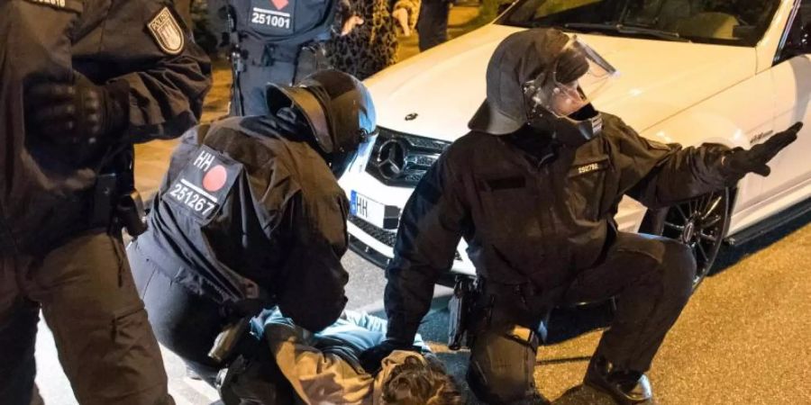 Polizisten nehmen am Zugang zum Schanzenviertel einen jungen Mann in Gewahrsam. Foto: Daniel Bockwoldt/dpa