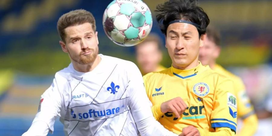 Darmstadts Immanuel Höhn und Dong-won Ji von Eintracht Braunschweig kämpfen um den Ball. Foto: Hauke-Christian Dittrich/dpa
