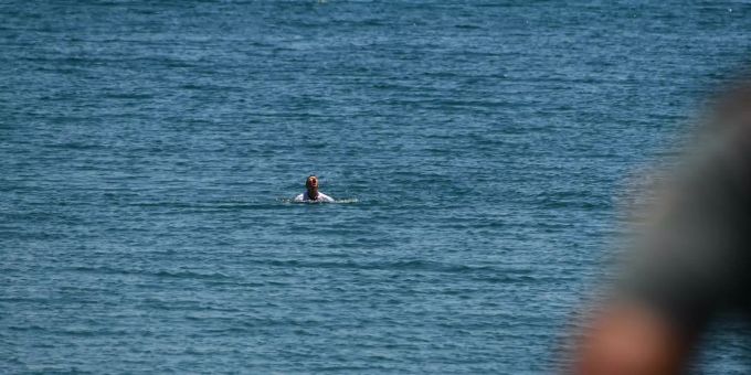 Ein junger Migrant schwimmt im Meer. Migranten