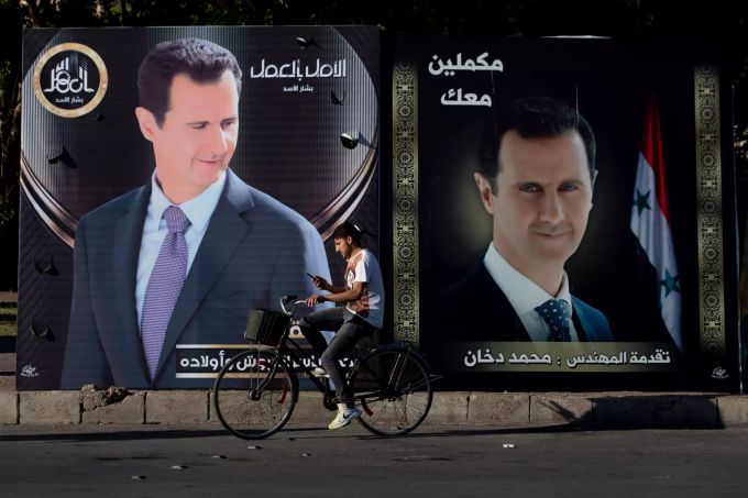 Ein Mann fährt auf einem Fahrrad an Wahlplakaten des syrischen Präsidenten al-Assad vorbei. Präsidentschaftswahl in Syrien