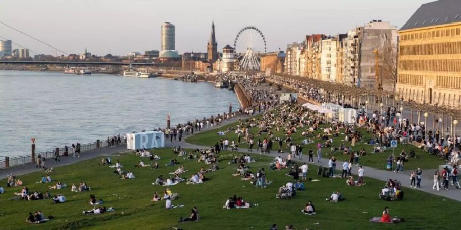 Menschen halten sich an der Rheinuferpromenade und den Rheinwiesen in Düsseldorf auf. Laut dem RKI breitet sich die sehr ansteckende Corona-Variante B.1.1.7 rasch in Deutschland aus. Foto: Jonas Güttler/dpa