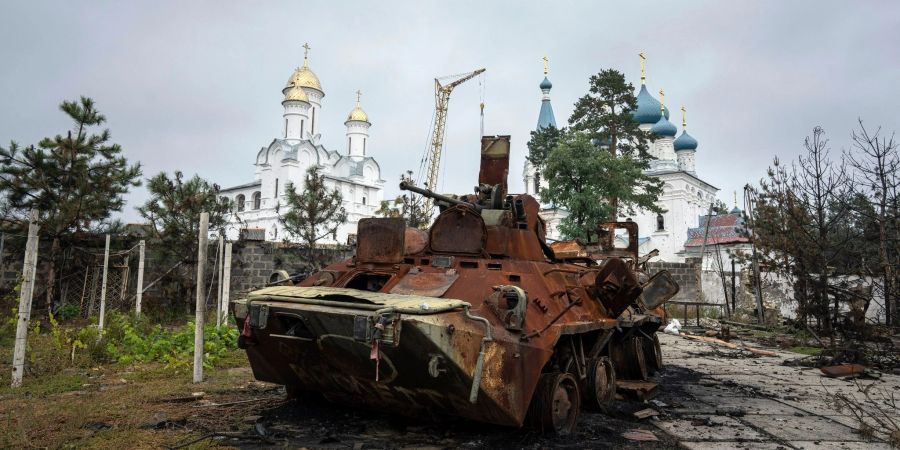 Ein zerstörter russischer Schützenpanzer steht vor einer Kirche in Isjum.