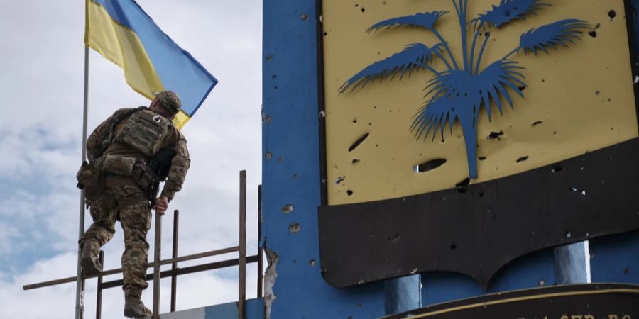 Ein ukrainischer Soldat stellt an der symbolischen Grenze zwischen den Gebieten Charkiw und Donezk eine Nationalflagge auf. Der Ukraine-Krieg hat viele Familien auseinander gerissen. (Symbolbild)