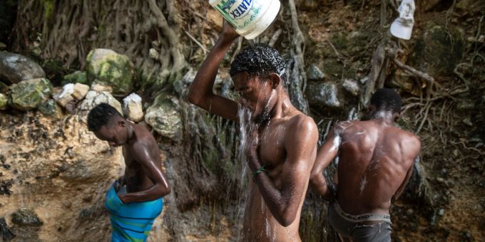 Menschen waschen sich in einer Schlucht in Port-Au-Prince. Menschen waschen sich in einer Schlucht in Port-Au-Prince.