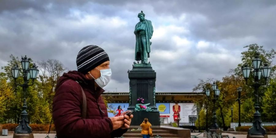 Mann mit Maske vor Puschkin-Denkmal in Moskau