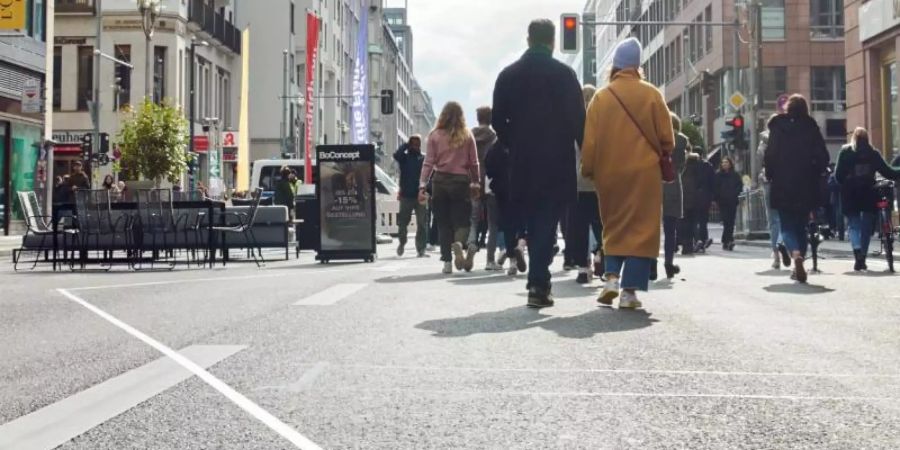 Menschen flanieren mitten auf der Friedrichstrasse. Das Modellprojekt zur autofreien Friedrichstrasse in Berlin wird jetzt in die Tat umgesetzt. Foto: Annette Riedl/dpa