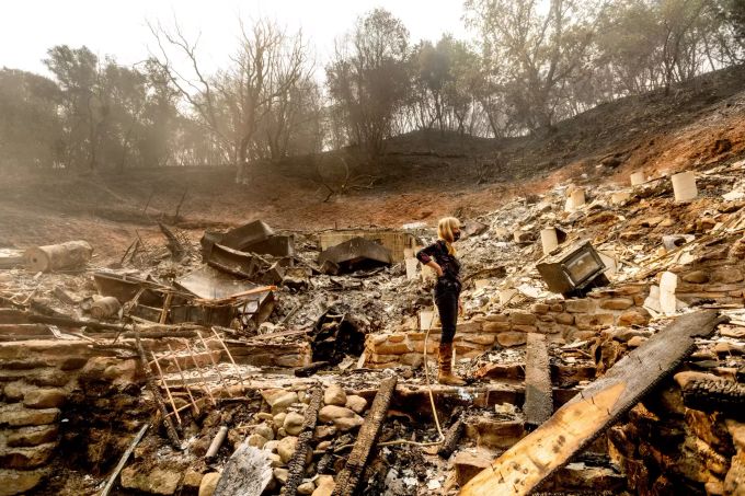 Eine Frau inspiziert die Überreste des Hauses ihres Partners. waldbrand kalifornien