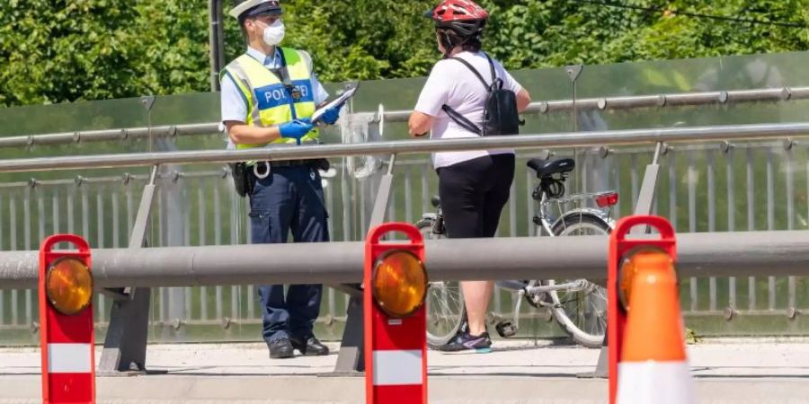 Ein deutscher Bundespolizist kontrolliert im Mai eine Fahrradfahrerin am bayerischen Grenzübergang Freilassing zwischen Deutschland und Österreich. Foto: Peter Kneffel/dpa