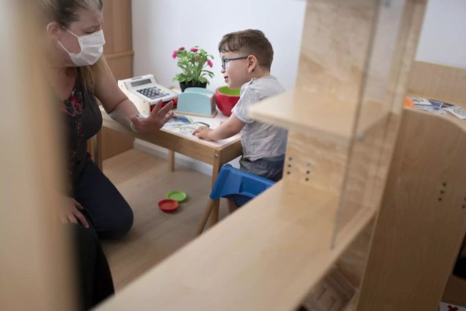 Eine Physiotherapeutin mit Hygienemaske arbeitet mit einen Jungen in der Kita 6e der Stiftung GFZ, aufgenommen am 9. Juli 2020 in Zürich. Kita Maske Physiotherapie