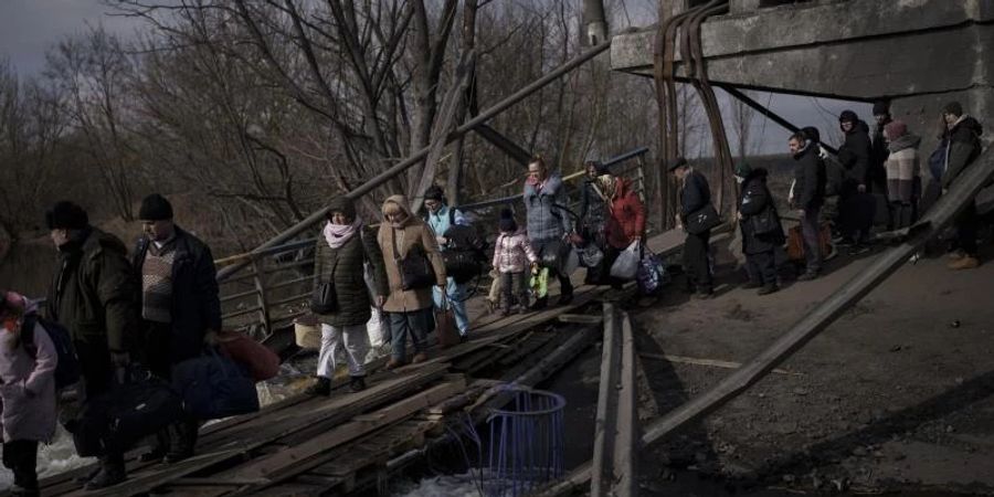 Auf der Flucht vor russischen Angriffen überqueren diese Ukrainer den Fluss Irpin unter einer zerstörten Brücke. Foto: Felipe Dana/AP/dpa