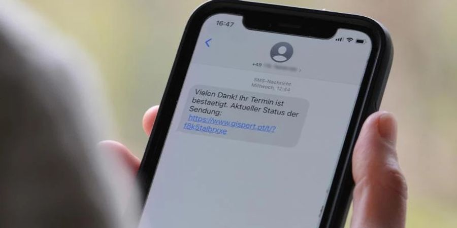 Eine Frau hält ein Smartphone in ihrer Hand, auf dessen Display eine Betrugs-SMS zu lesen ist. Foto: Wolf von Dewitz/dpa