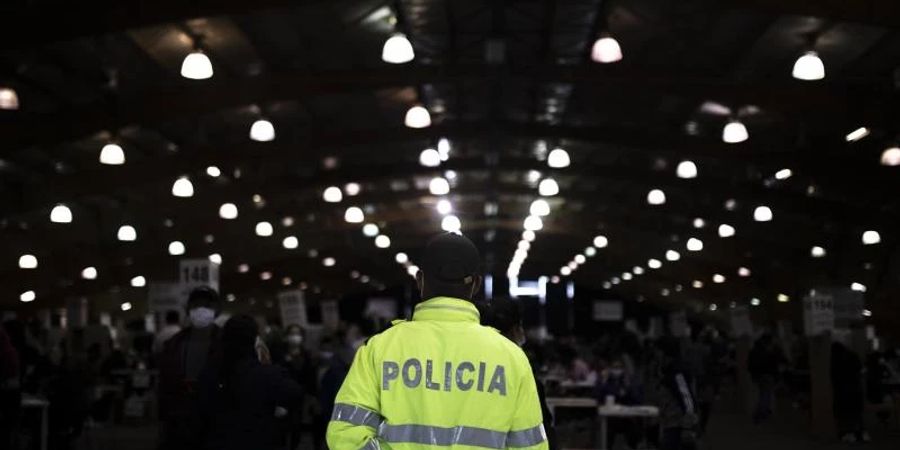 Ein Polizist in Kolumbiens Haupstadt Bogotá beobachtet das Geschehen in einem Wahllokal. Foto: Ivan Valencia/AP/dpa