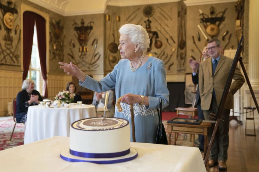 Anstatt ein Stück zu schneiden, steckt Queen Elizabeth einfach das Messer in die Mitte des Kuchens.