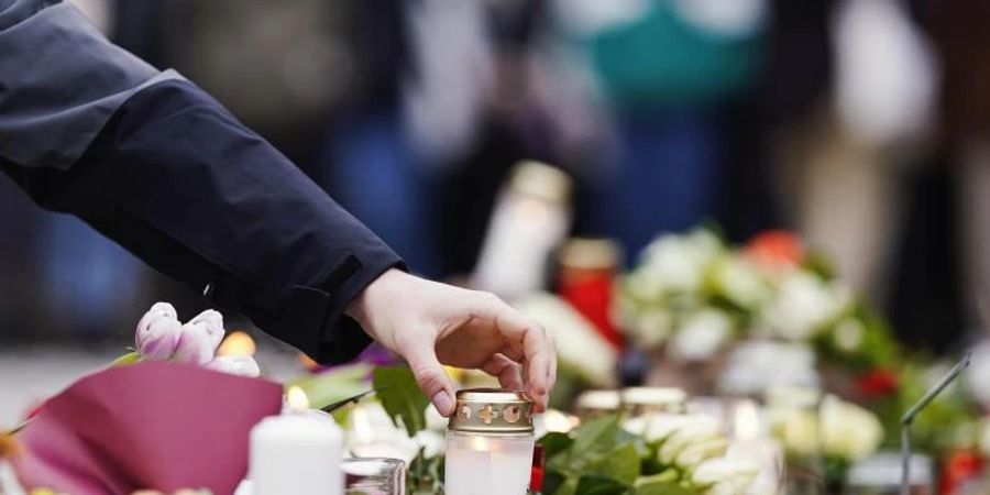 Menschen haben vor einem Gebäude der Heidelberger Universität Blumen und Kerzen niederlegt. Foto: Uwe Anspach/dpa