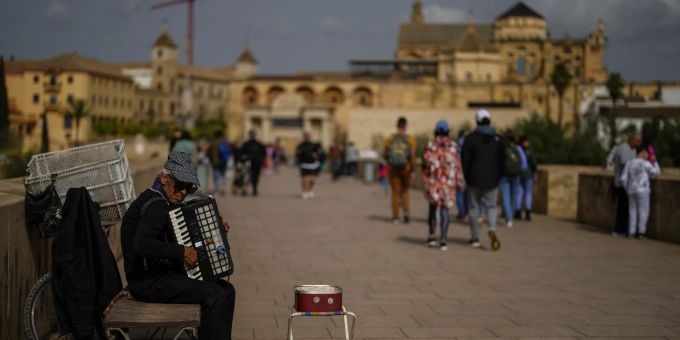 Ein Strassenmusiker spielt Musik auf der römischen Brücke mit der Grossen Moschee von Córdoba im Hintergrund am Samstag, 26. März 2022. Spain Daily Life