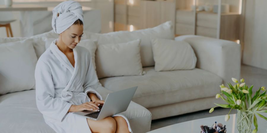 Frau im Bademantel am Laptop