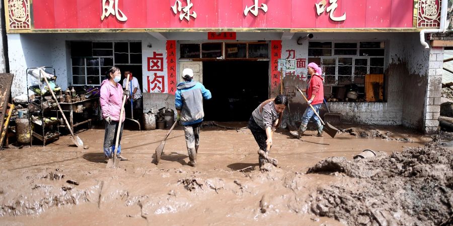 Anwohner entfernen Schlamm von ihrem Grundstück in der nordwestchinesischen Provinz Qinghai.