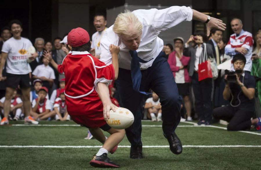 Der nicht sehr diplomatische Top-Diplomat bei einem Besuch in Japan, wo er in den Strassen von Tokyo Street Rugby spielt und prompt einen Jungen umrempelt.