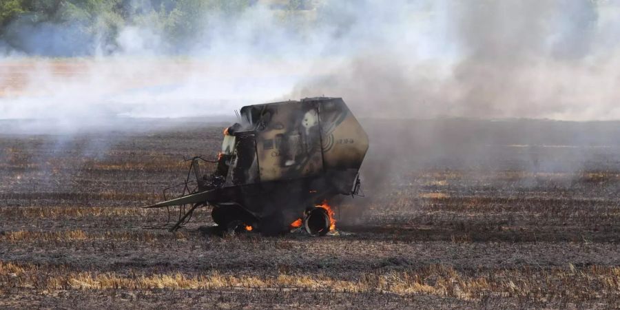 Strohballenpresse und Feld geraten in Brand.